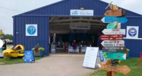 A blue barn with a signpost of chapter destinations in front