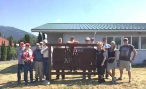 A group of members at the Concrete airport sign