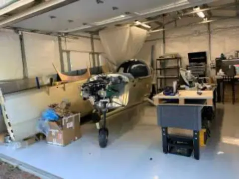 A Sling fuselage with its engine mounted, in a white-walled hangar workshop