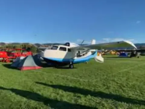 Airplanes and tents parked on the grass at the fly-out
