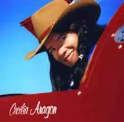A smiling woman in a cowboy hat leaning out of a red airplane cockpit, the name Cecilia Aragon painted below