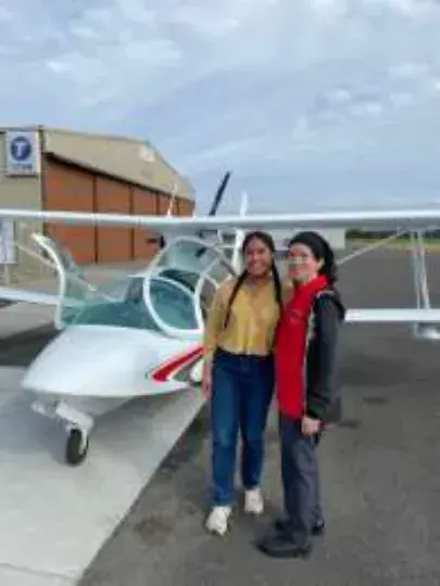 A couple standing beside a white low-wing airplane