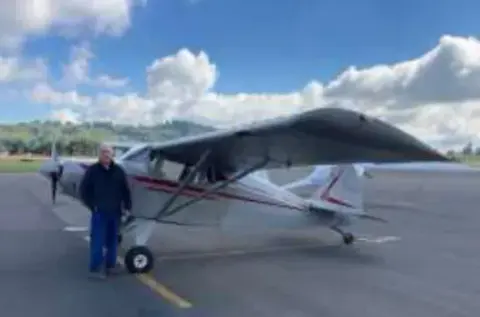 A man standing beside a white high-wing airplane