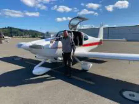A man standing beside a low-wing airplane on the ramp
