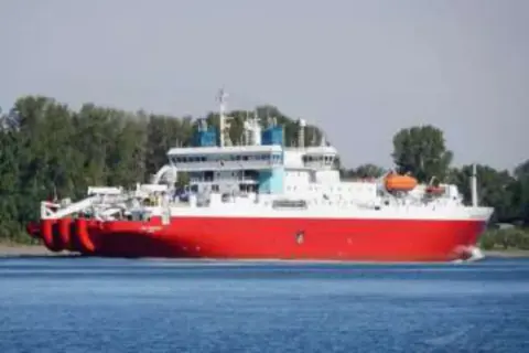 A large red and white ship on the water
