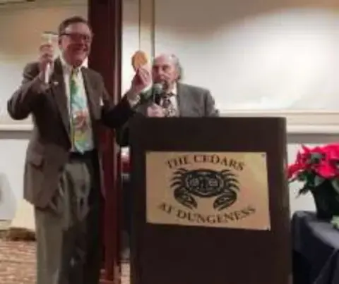 A man speaking at a podium beside another man