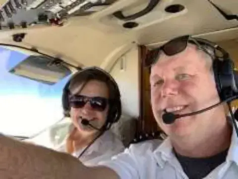Two pilots in headsets taking a selfie in the cockpit