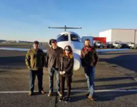 Four people on the ramp in front of a white jet