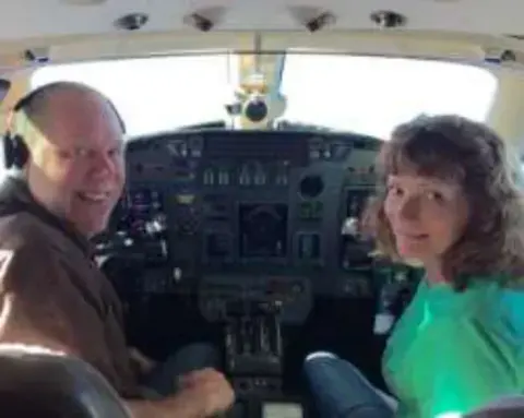 A man and a woman in the front seats of a cockpit