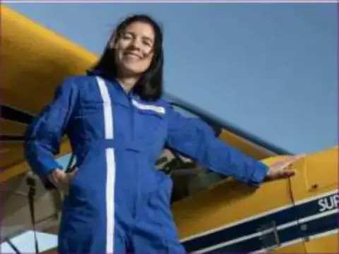Cecelia in a blue flight suit beside a yellow airplane