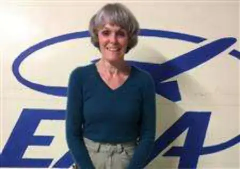 Colette in a teal sweater in front of an EAA logo
