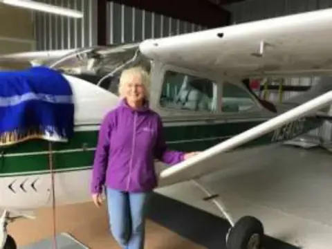 Dava standing beside a white high-wing airplane in a hangar
