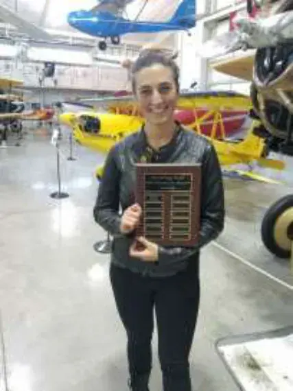 A young woman holding a plaque in an aviation museum