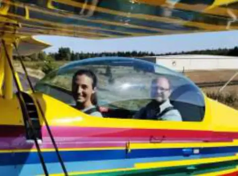 Two people in the cockpit of a brightly painted airplane