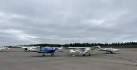 Several small airplanes parked on the ramp