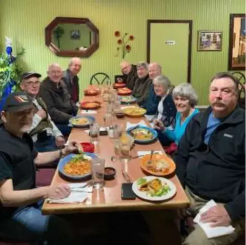 Members seated at a long dinner table in a restaurant