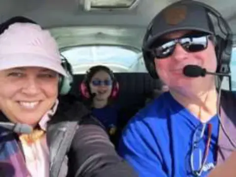 Three people wearing headsets in a cockpit