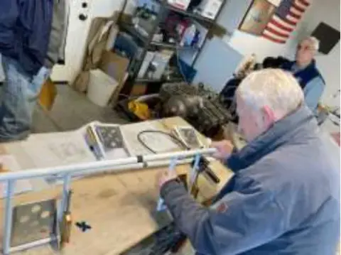 An older man working at a cluttered workbench