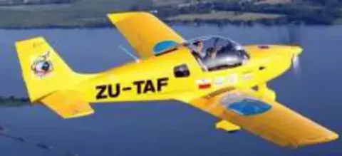 A yellow low-wing airplane with registration ZU-TAF in flight