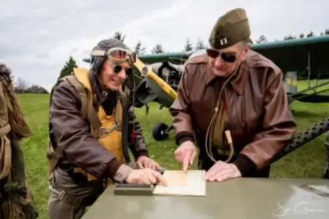Two men in vintage military flight jackets looking at a map