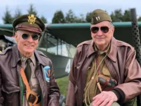 Two older men in World War II style uniforms and caps