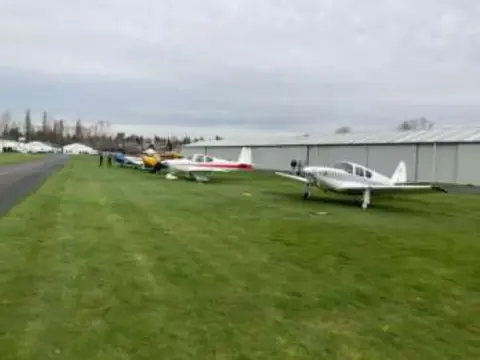 Several small airplanes parked on a grass field