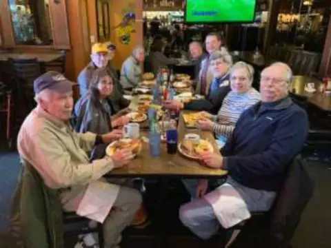 Members seated at a long restaurant table