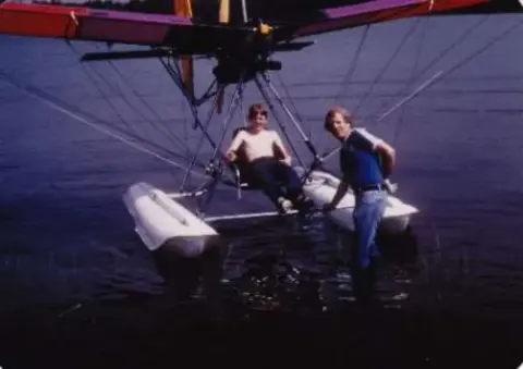 Two people in a hang glider style amphibious trike over water