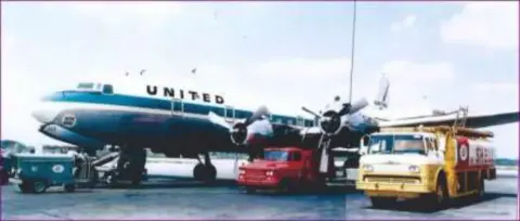 A United Airlines propliner on the ramp with ground vehicles