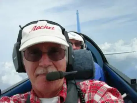 A man in a cap and headset in a cockpit
