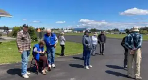 Fly-out members standing in a group by a marina