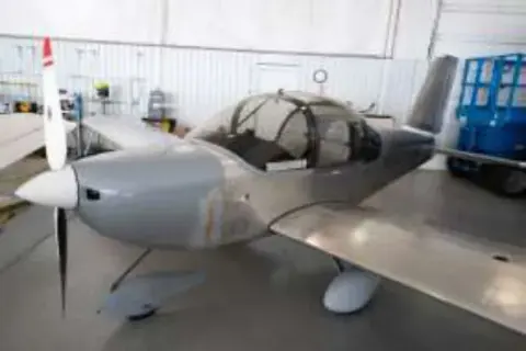 A gray RANS S-19 low-wing airplane in a hangar