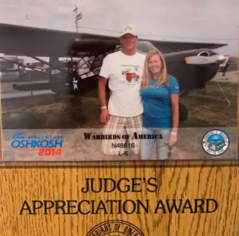 A couple holding a Judge's Appreciation Award display