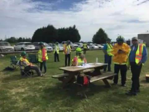 Volunteers in safety vests at picnic tables on the grass during the DART and CERT exercise