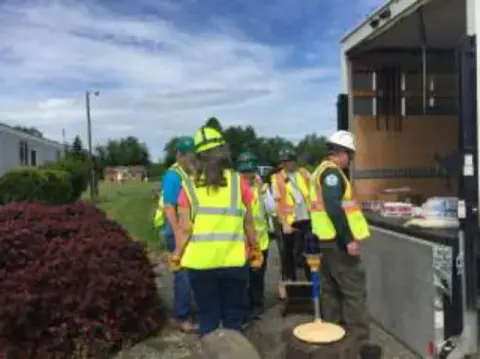 CERT volunteers in vests and hard hats beside an open supply truck