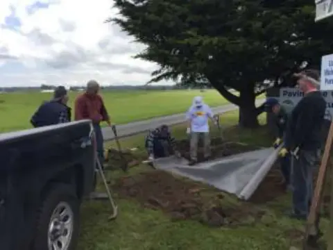 Volunteers working on the patio site near a pickup truck