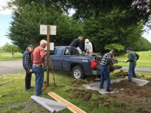 Volunteers laying out the brick patio area near a pickup truck