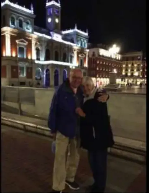A couple posing at night in front of a lit historic building