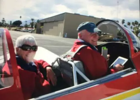 Two men in an open-cockpit red airplane