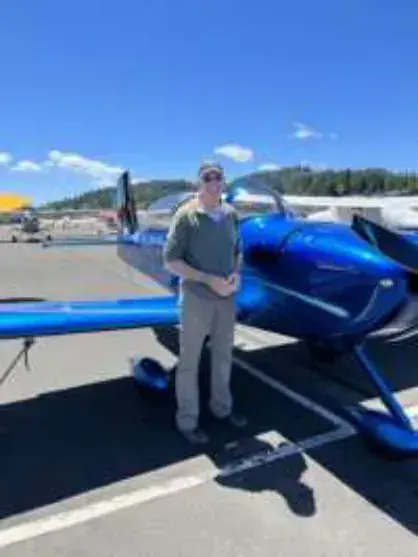 A man standing next to a blue low-wing airplane