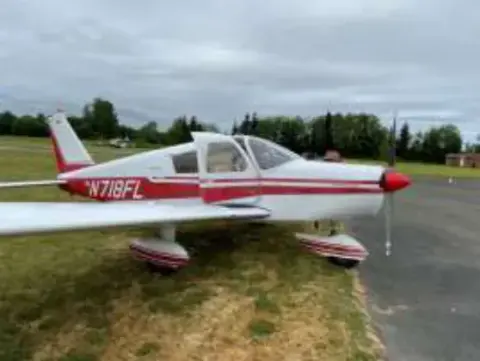 A red and white low-wing airplane parked on grass