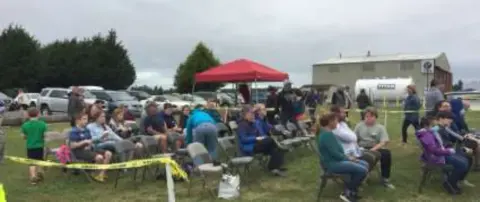 People seated under tents at the rally