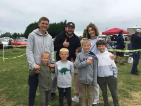 Two men and four children posing on the grass at a Young Eagles rally