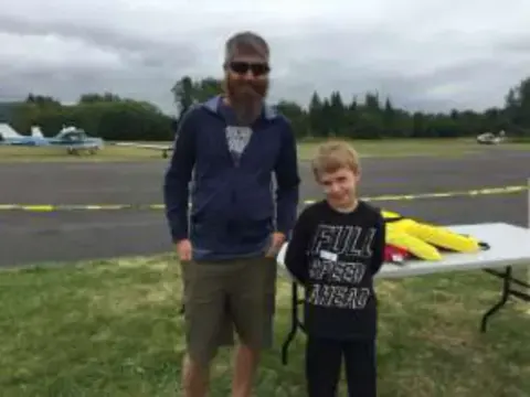 A man and a boy standing on the grass at the rally