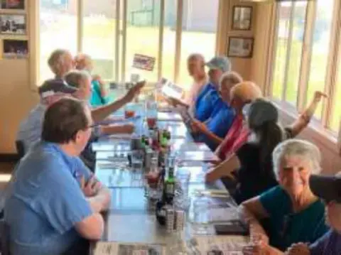 Members seated at tables inside the cafe