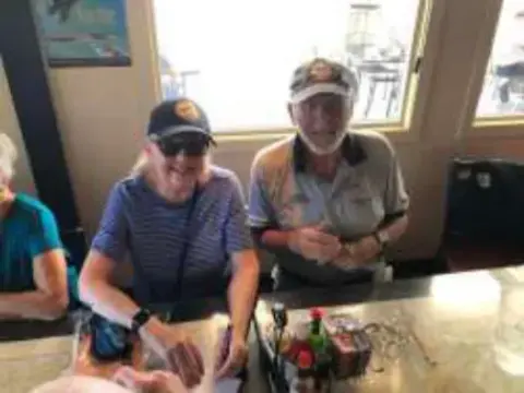 Two men seated at a cafe table smiling