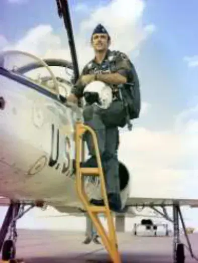 A pilot in a flight suit climbing into a vintage jet