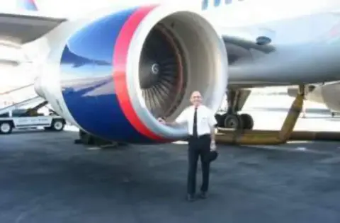 A man standing in front of a large airliner engine