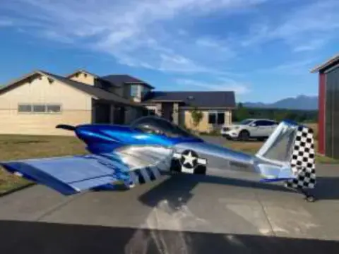 A blue and white homebuilt airplane parked on the grass