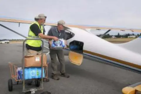 Volunteers loading supplies into a small airplane